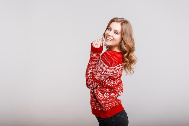 Modelo de mujer europea hermosa en un suéter rojo de moda con una impresión en el estudio