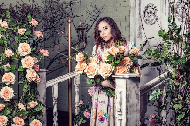 Modelo de mujer hermosa en los colores de las rosas en el jardín con un hermoso cambio de imagen