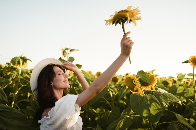 Modelo de mujer joven atractiva posando en campo de girasoles