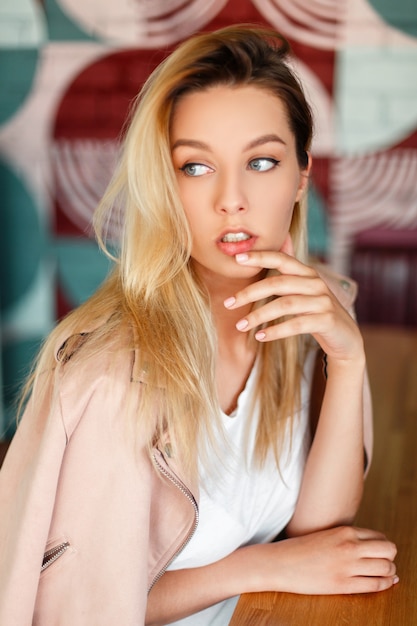 Modelo de mujer joven hermosa en una chaqueta de moda rosa se sienta