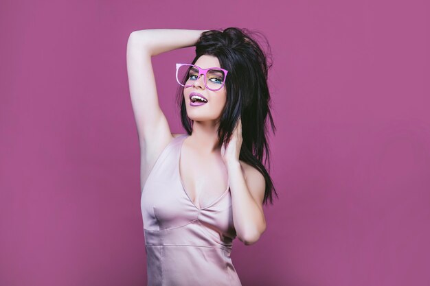 Modelo mujer joven y hermosa en el estilo del arte pop sobre un fondo rosa en vasos pintados de rosa