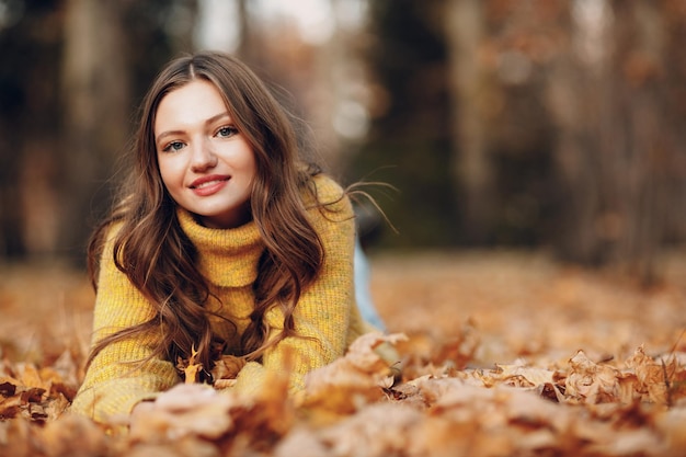 Modelo de mujer joven en el parque de otoño con hojas de arce de follaje amarillo Moda de temporada de otoño