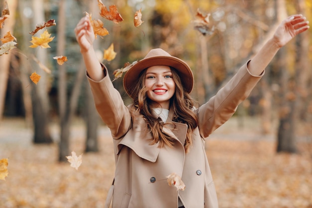 Modelo de mujer joven en el parque de otoño con hojas de arce de follaje amarillo Moda de temporada de otoño