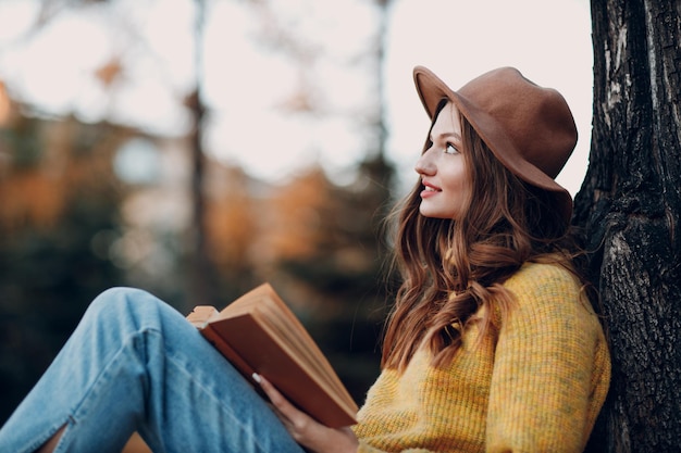 Modelo de mujer joven en el parque de otoño con hojas de arce de follaje amarillo Moda de temporada de otoño