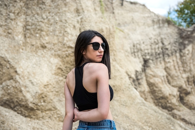 Modelo de mujer joven posando y descansando afuera en una cantera de arena. Mujer atractiva relajante