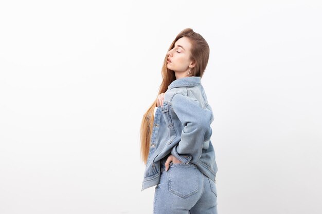 Modelo de mujer de moda sexy vestida con jeans y chaqueta de mezclilla sobre fondo blanco