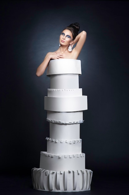 Modelo de mujer con peinado y maquillaje con un vestido de papel, sobre fondo negro.