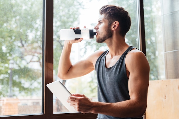 Modelo na academia com garrafa e tablet