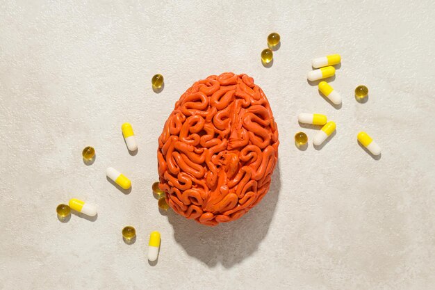 Foto modelo naranja del cerebro humano con píldoras y vitaminas