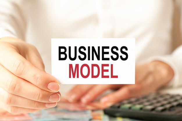 Modelo de negocio está escrito en una tarjeta de presentación blanca La mano de un hombre sostiene una tarjeta de papel blanco Fondo blanco Concepto de publicidad y negocios Desenfoque