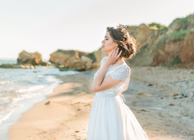 Modelo de novia de moda en vestido de novia de lujo en el océano o la costa del mar