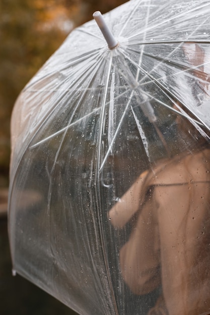 Modelo con paraguas transparente bajo la lluvia en otoño. de cerca. vista trasera