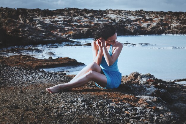 Modelo de pelo oscuro está posando con una laguna azul sobre un fondo