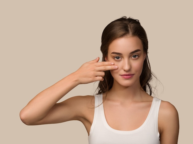 Foto modelo de pelo rizado de la belleza de la piel sana de la cara de la mujer hermosa. tocando su rostro color fondo marrón