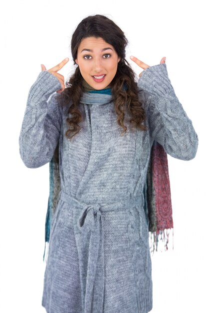 Foto modelo de pelo rizado con ropa de invierno señalando su cabeza