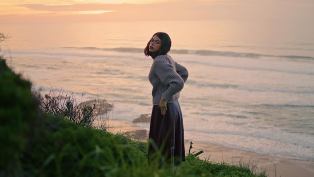 Modelo pensativo posando a orillas del mar en suéter acogedor chica tranquila relajarse noche naturaleza