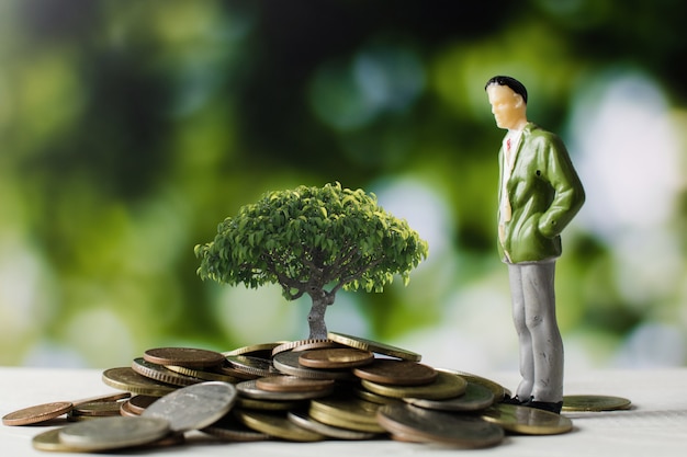 Modelo de personas de negocios con monedas de dinero con pequeño árbol que crece