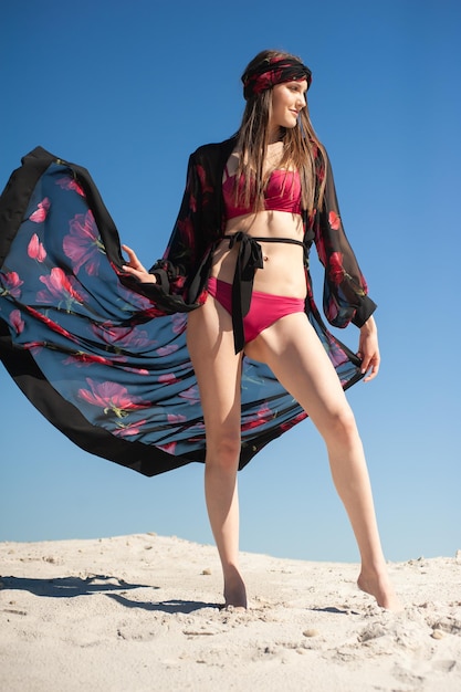 Una modelo posa en la playa con un kimono con estampado de mariposas.