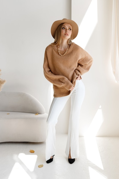 Un modelo con ropa elegante de otoño y un sombrero en un estudio luminoso con maquillaje. compras de otoño