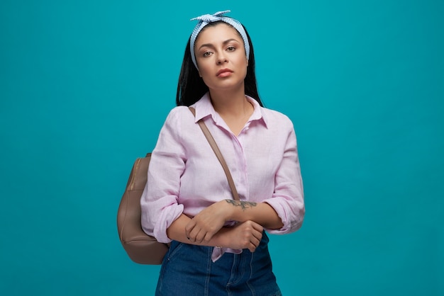 Modelo en ropa de moda con bolso marrón en el hombro.