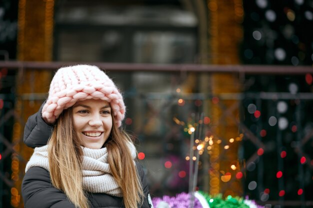 Modelo rubia rubia fresca con traje de invierno celebrando el año nuevo en la calle con luces de Bengala. Espacio para texto