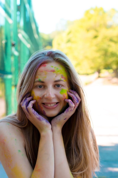 Modelo rubia sonriente con polvo de color Gulal en la cara