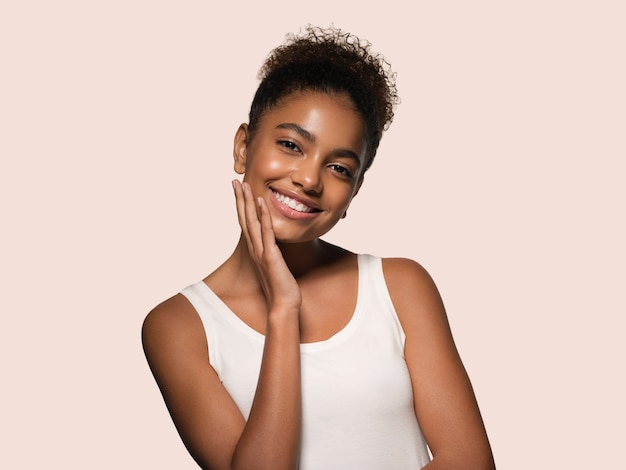 Modelo sonriente de la cara de la piel negra de la mujer de la belleza que toca su cara. Fondo de color. Rosado