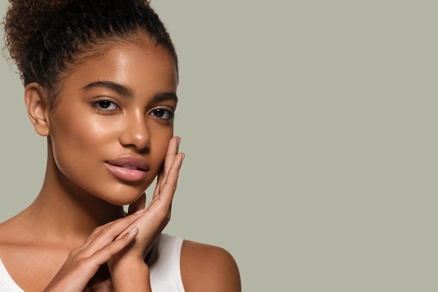 Modelo sonriente de la cara de la piel negra de la mujer de la belleza que toca su cara. Fondo de color. Verde