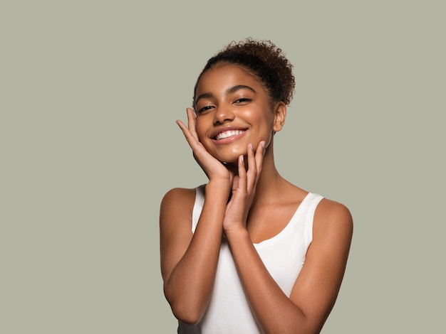 Modelo sonriente de la cara de la piel negra de la mujer de la belleza que toca su cara. Fondo de color. Verde