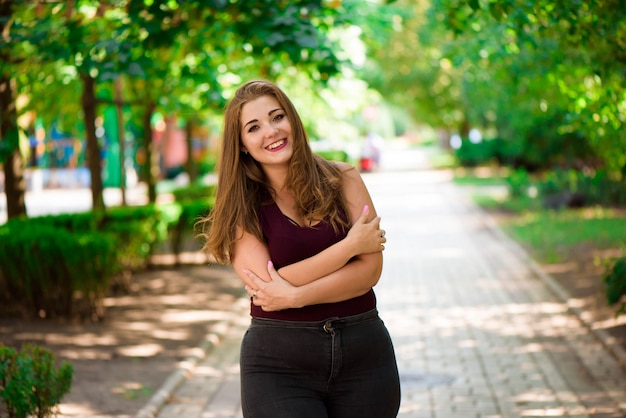 Modelo de talla grande en ropa casual, cuerpo femenino con sobrepeso en un parque al aire libre.