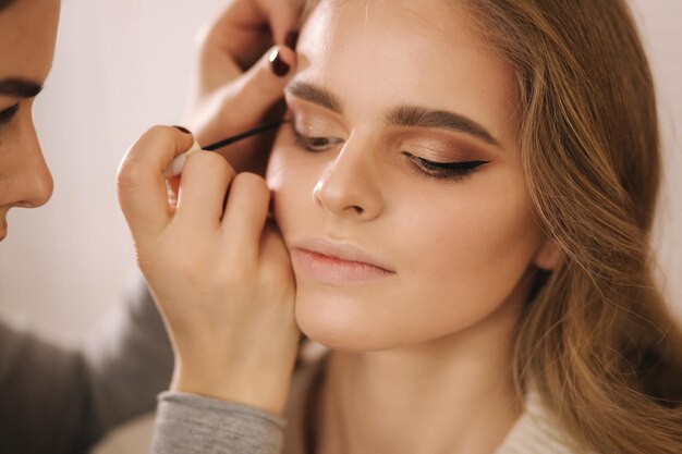 Modelo tiene un maquillaje de maquillador en salón de belleza Primer plano de la cara del modelo con maquillaje