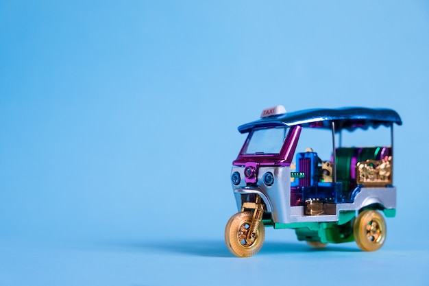 Modelo Toy tuk tuk isolado na parede azul. Táxi tradicional tailandês em Bangkok Tailândia. Lembrança