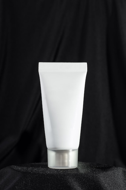 modelo de tubo blanco limpio de crema para las manos sobre un fondo negro oscuro