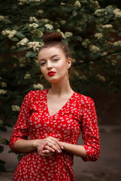 Modelo con un vestido rojo de verano con labios rojos y cabello recogido.