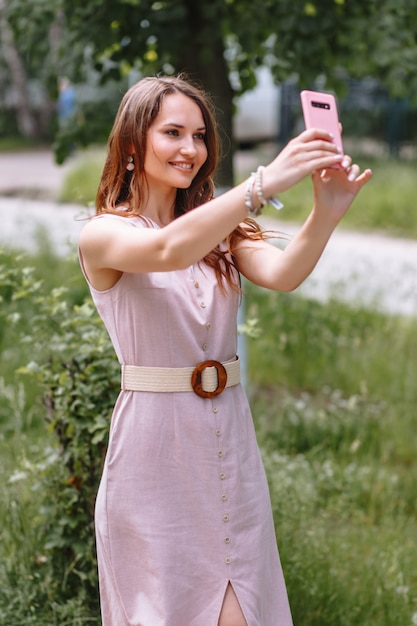 Una modelo con un vestido rosa claro tomando una selfie