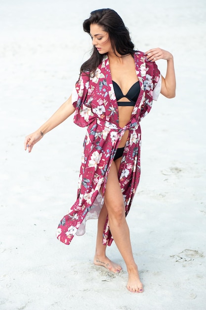 Foto una modelo viste un kimono y un bikini negro.