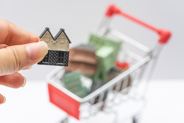 Modelos de casas apiladas en carrito de compras.