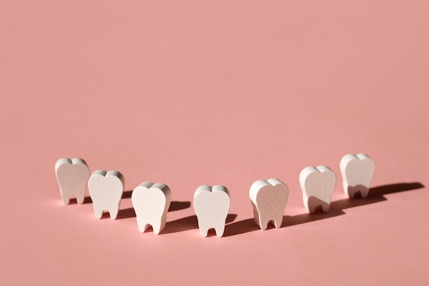 Modelos de dentes alinhados formando um sorriso em um fundo rosa