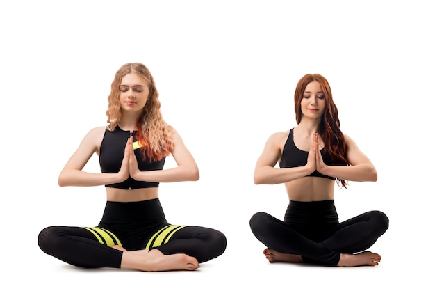 Modelos de fitness sexy com blusa preta e legging fazendo ioga