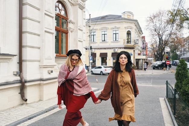 Modelos de mujeres de moda sin preocupaciones en elegantes ropas de otoño y gafas. Chicas de moda joven en ropa de lana tejida con estilo y sombreros sobre ciudad urbana, retrato de otoño.