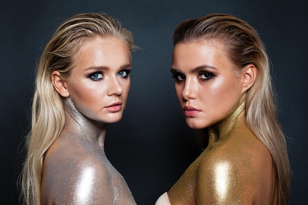 Modelos de mujeres perfectas con maquillaje de brillo dorado y plateado sobre fondo oscuro