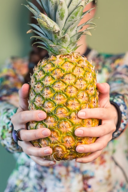 Modemädchen, das Ananas zwischen ihren Händen hält