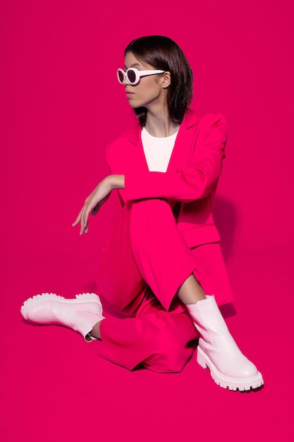 Modemodell aus Asien in rosa Anzug, weißen Stiefeln und Sonnenbrille