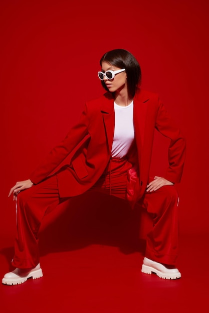 Modemodell aus Asien in rotem Anzug, weißen Stiefeln und Sonnenbrille