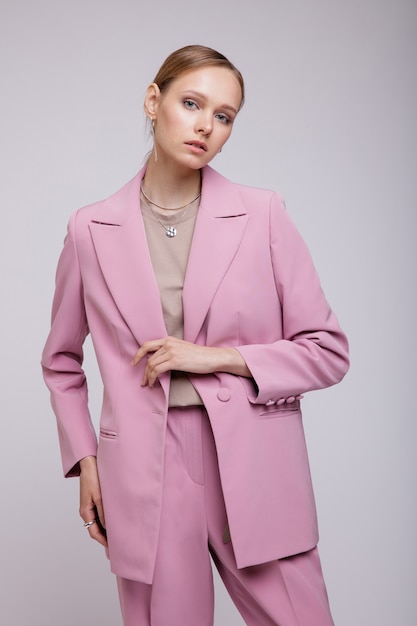 Modemodell in rosa übergroßer Anzugjacke, die auf weißem Hintergrund posiert Studio Shot