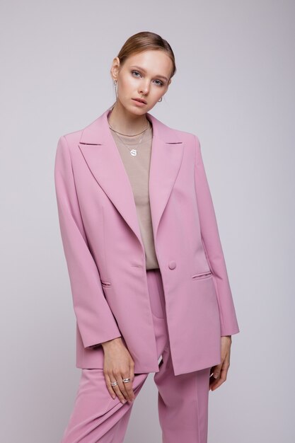 Modemodell in rosa übergroßer Anzugjacke, die auf weißem Hintergrund posiert Studio Shot