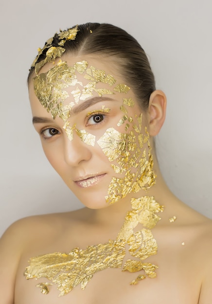 Modeporträt der wunderschönen brünetten Frau mit Kunst-Make-up aus goldener Folie