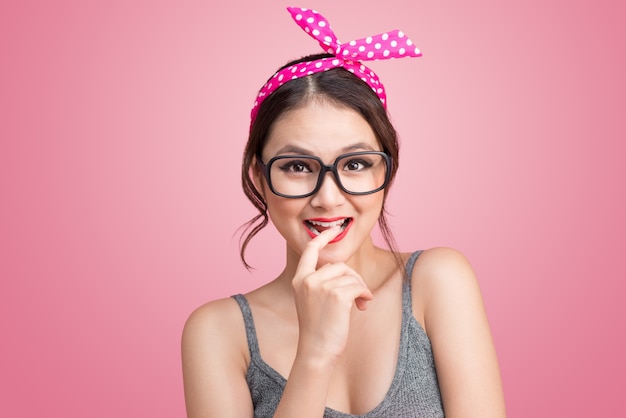 Modeporträt des asiatischen Mädchens mit der Sonnenbrille, die auf rosa Hintergrund steht.