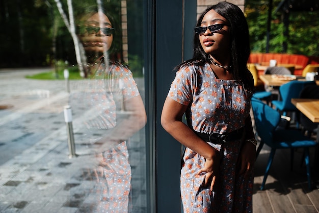 Modeporträt einer afroamerikanischen Frau in langem Kleid und Brille im Innenbereich