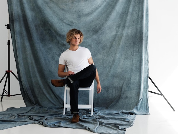 Foto modeporträt eines jungen mannes in weißem hemd posiert im studio vor blauem hintergrund